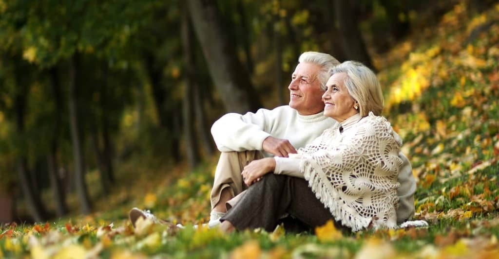 Smiling older couple sitting together in an autumn park